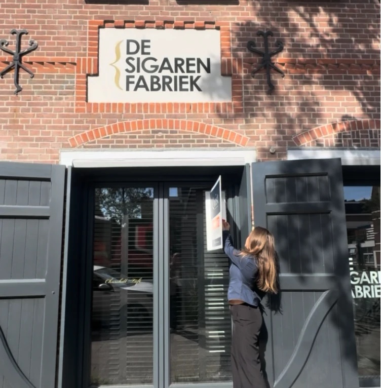 Een poster wordt opgehangen bij de ingang van De Sigarenfabriek in Utrecht
